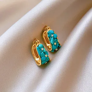 Close-up detail shot of vintage gold hoop earrings showcasing turquoise stones and zirconia.