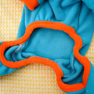 Close-up detail of blue fleece pet clothing with orange contrast trim, cozy fabric.