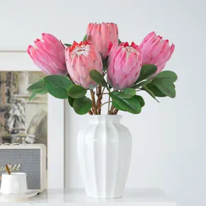 Moderne noordse kunstmatige protea bloemenboeket met witte keramische vaas voor huisdecoratie.