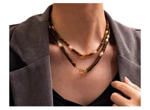Detailed view of layered beaded necklace with tiger eye stones and pearls on model neck.
