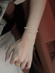 Primer plano de una pulsera de plata doble con perlas y circonitas brillantes elegantes.