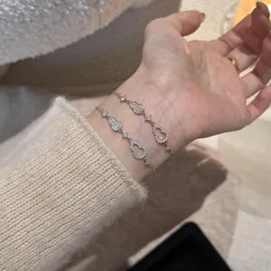 Vista detallada de pulseras de trébol de circonita cúbica brillante de doble capa en la muñeca.