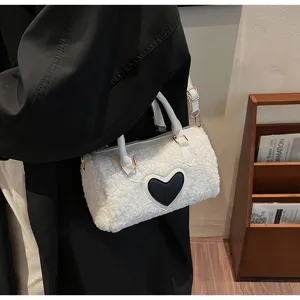 Détail de sac Boston duveteux blanc avec écusson cœur noir, bandoulière élégante.