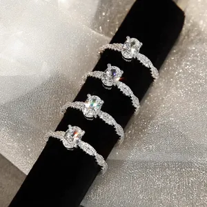 Primer plano de anillos de circonita ovalada brillante con bandas trenzadas sobre terciopelo.