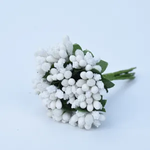 Close-up detail of white artificial berries and green leaves for DIY handmade crafts.