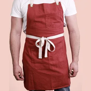 Cotton linen kitchen apron with front pockets, adjustable straps and metal grommets detail.