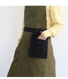 Vista dettagliata del grembiule da lavoro in tela con tasche pratiche e marsupio integrato.