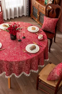 Nappe ronde festive en jacquard rouge avec motif floral doré et dentelle à franges pour table.