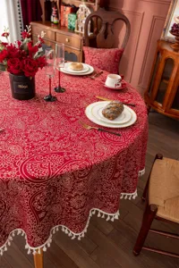 Nappe jacquard festive rouge pour table ronde vue de détail avec frange blanche.