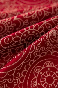 Gros plan sur la texture du tissu de la nappe jacquard rouge festive aux motifs dorés.