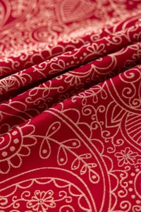 Gros plan d'un tissu jacquard rouge festif avec un élégant motif floral doré et texture.