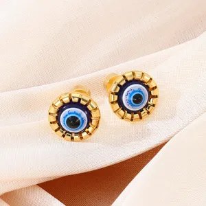 Close-up detail of trendy evil eye gold stud earrings, featuring intricate blue enamel drip oil.