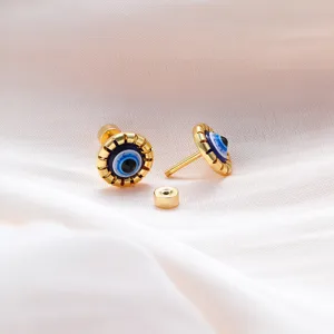 Closeup detail of gold evil eye stud earrings with screw backs, showing intricate blue enamel design.