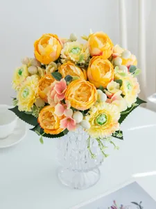 Artificial flower bouquet arrangement detail shot with yellow peonies in clear glass vase.