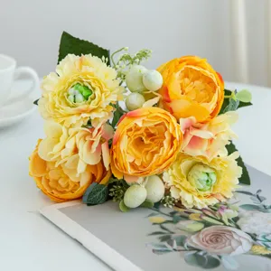 Close-up detail of vibrant artificial yellow and orange flower bouquet on clean white tabletop.