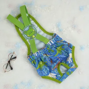 Vista detallada de pantalones para mascotas con estampado de dinosaurio azul y correa verde y rana.
