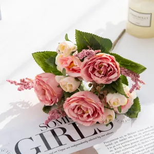 Dettaglio di bouquet di peonie artificiali, fiori di seta rosa tenue con foglie verdi.