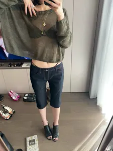 Women's slim-fit contrast stitch cropped raw denim jeans and sheer knit top outfit.