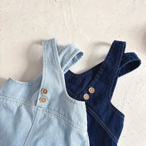 Primo piano dettagliato delle bretelle della salopette in denim per neonati con bottoni.