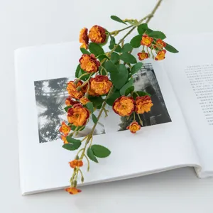 Close-up detail of artificial small rose flower branch placed on book, pastoral home decor prop.