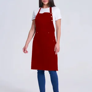 Detail view of the red bib apron featuring adjustable neck straps, buttons, and front utility pockets.