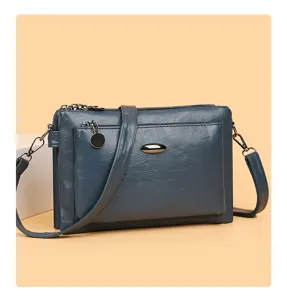 Detail view of dark blue PU leather multi-layer crossbody bag with zippers and metal accent.