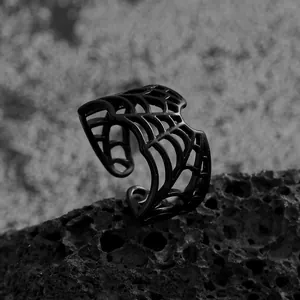 Close-up macro detail of gothic black spider web open ring on textured volcanic rock