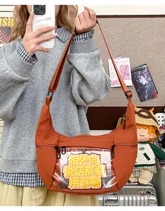 Detalle de un bolso ita marrón en forma de luna con ventana frontal transparente
