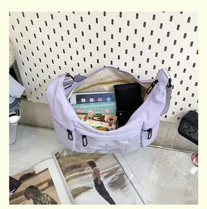 Vista detallada del bolso bandolera de lona lavanda con bolsillo transparente y su contenido.