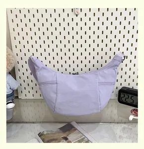 Vista frontal detallada de un bolso bandolera de lona lavanda con forma de media luna