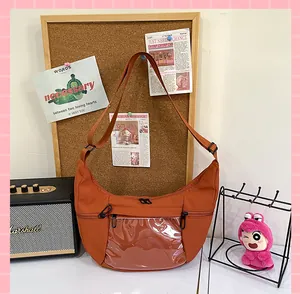 Detalle de un bolso ita naranja con forma de media luna y ventana de PVC transparente.