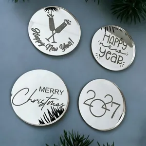 Close-up van vier spiegelende zilveren acryl taarttoppers met Kerst- en Nieuwjaarswensen