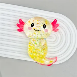 Gelbes glitzerndes Axolotl-Squishy-Spielzeug mit rosa Kiemen auf weißem Tablett