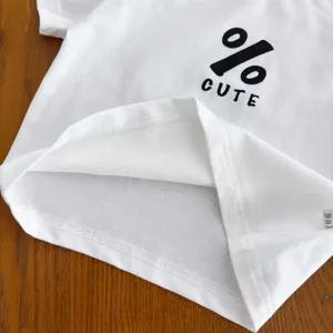 Dettaglio orlo t-shirt neonato bianca, tessuto cotone morbido, stampa carina, primo piano.