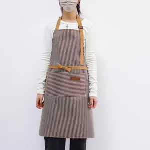 Tablier de cuisine à rayures avec bretelles en cuir marron et grande poche pratique.