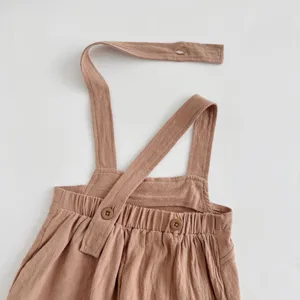 Close-up detail of infant baby solid color overall romper straps featuring cute buttons and texture.