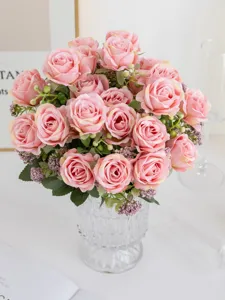 Artificial pink rose bouquet in clear glass vase, beautiful home desktop floral decor.