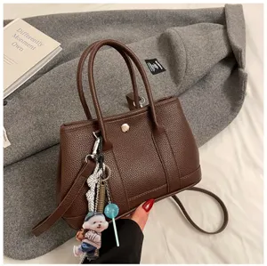 Stylish brown leather tote bag with cute charms, versatile shoulder and crossbody bag.