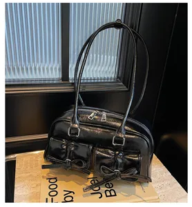 Détail de sac porté épaule en cuir verni noir, nœud ballerine chic, sac à main sous-bras.
