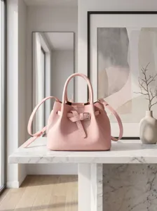 Close-up detail of the elegant pink leather bucket handbag with buckle and strap on marble counter.
