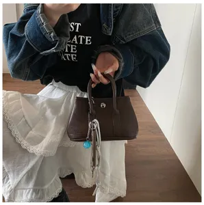 Chic brown leather handbag featuring a top handle and trendy keychain for daily commuting.