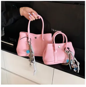 Detailed view of stylish pink PU leather tote bag with cute bear charm for daily commute.
