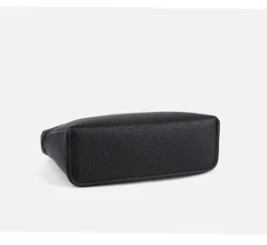 Detailed view of the black textured leather mini handbag bottom, showing fine stitching.