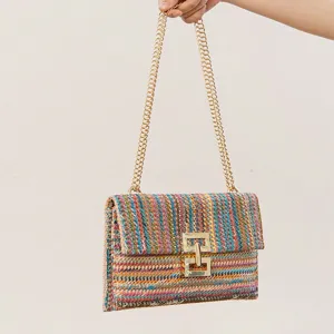 Detailed view of the colorful woven straw shoulder bag with a gold chain strap and metal lock.