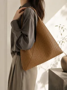 Detail shot of a brown woven leather shoulder bag showcasing texture and stylish underarm design.