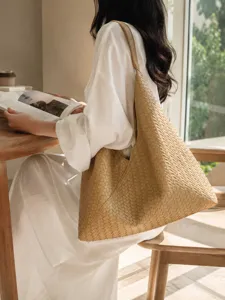 Detail shot of a beige woven leather shoulder bag, chic hobo tote design for summer style.