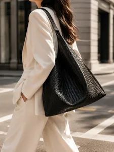 Detail shot of a stylish black woven leather shoulder bag, large capacity hobo tote style.