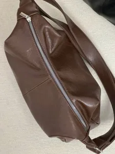 Brown soft leather crossbody bag detail, vintage shoulder bag texture and zipper close-up view.