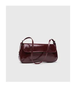 Burgundy patent leather baguette bag detail, minimalist flap shoulder handbag style.