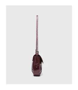 Red patent leather baguette shoulder bag detail showing slim strap and flap structure.